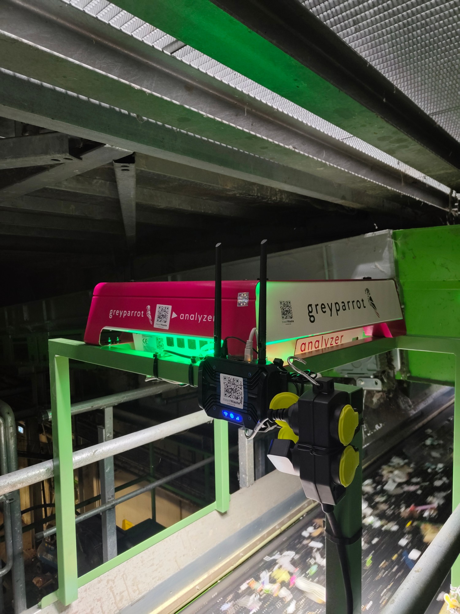Les deux analyseurs Greyparrot et leur routeur, fixés sur un châssis vert au-dessus d’un convoyeur du centre de tri de Chézy